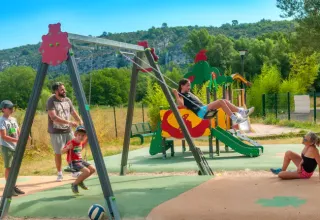 Børn og voksne nyder legepladsen med gynger og rutsjebane på Seasonova Camping Les Prés du Verdon.