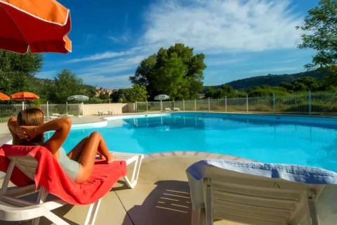 Frau entspannt auf einem Liegestuhl am Pool im Seasonova Camping Les Prés du Verdon, Provence-Alpes-Côte d’Azur.