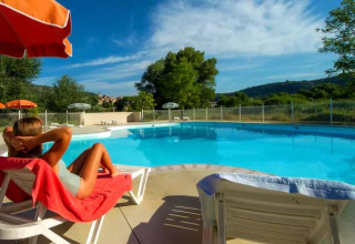 Kvinde slapper af på en liggestol ved poolen på Seasonova Camping Les Prés du Verdon i Provence-Alpes-Côte d’Azur.