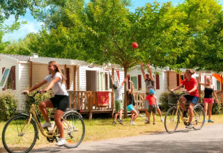 Gezinnen genieten van de vakantie bij Seasonova Camping Les Prés du Verdon, fietsend en spelend bij stacaravans.