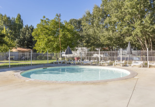 Circular swimming pool with sun loungers and umbrellas at Seasonova Camping Les Prés du Verdon, France.