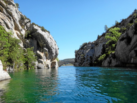 Naturskønt vandløb omgivet af klippevægge og grøn vegetation nær Quinson, Provence-Alpes-Côte d’Azur.