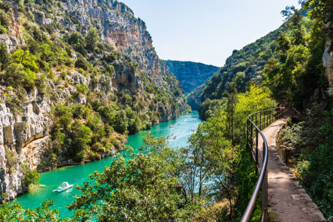 Blick auf eine türkisfarbene Schlucht nahe Quinson, Provence-Alpes-Côte d’Azur, umgeben von Felsen und Wald.