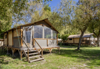 Safari-Zelt Comfort Lodge auf Seasonova Camping Les Prés du Verdon in Frankreich, umgeben von Bäumen.