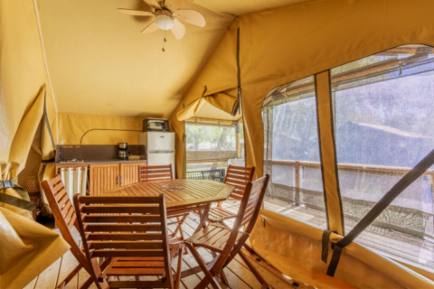 Innenansicht des Comfort Lodge Safari-Zelts mit Holzmöbeln und Küchenzeile bei Seasonova Camping Les Prés du Verdon.
