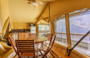 Innenansicht des Comfort Lodge Safari-Zelts mit Holzmöbeln und Küchenzeile bei Seasonova Camping Les Prés du Verdon.