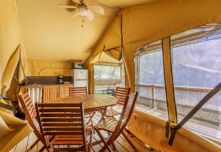 Innenansicht des Comfort Lodge Safari-Zelts mit Holzmöbeln und Küchenzeile bei Seasonova Camping Les Prés du Verdon.