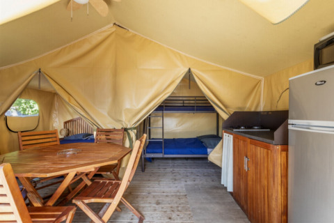 Innenansicht eines Comfort Lodge Safari-Zeltes bei Seasonova Camping Les Prés du Verdon mit Möbeln und Küche.