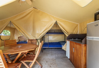 Innenansicht eines Comfort Lodge Safari-Zeltes bei Seasonova Camping Les Prés du Verdon mit Möbeln und Küche.