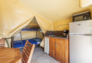 Innenaufnahme des Comfort Lodge Safari-Zeltes mit Küche, Etagenbetten, Esstisch und Schränken auf Campingplatz.