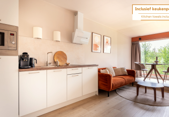 Modernes Wohnzimmer und Küche im Tiny House XL bei De Kremmer, Niederlande, mit Sofa und Esstisch.
