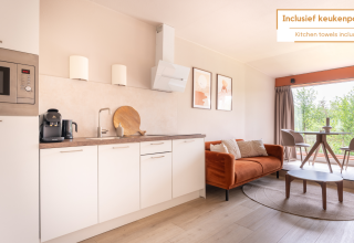 Moderne woonkamer en keuken in Tiny House XL bij De Kremmer, Nederland, met bank, tafel en grote ramen.