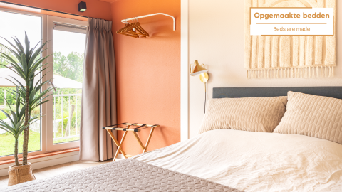 Slaapkamer in Tiny House XL bij De Kremmer, Nederland, met comfortabel bed, grote ramen en moderne warme inrichting.