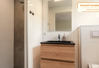 Modernes Badezimmer in einem Tiny House mit Dusche, Holzwaschbecken und Spiegel. Handtücher inklusive.