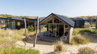 Vista esterna di un Adventure Lodge a Bloemendaal aan Zee, Paesi Bassi, circondato da dune e vegetazione.