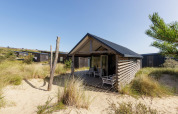 Adventure Lodge a Bloemendaal aan Zee, Paesi Bassi, circondata da dune di sabbia e erba sotto il sole.
