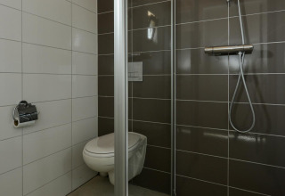 Salle de bain moderne à l’Adventure Lodge, Bloemendaal aan Zee, avec WC suspendu et douche vitrée.