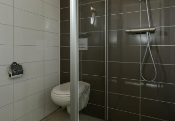 Moderne badeværelse på Adventure Lodge, Bloemendaal aan Zee, med ophængt toilet og brusekabine.