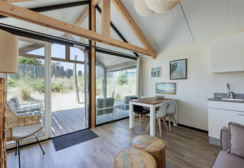 Bright, modern interior of Adventure Lodge at Bloemendaal aan Zee, Netherlands, with large windows and dune view.