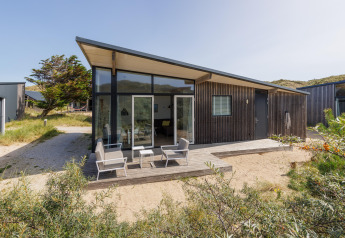 Moderne Lodge Sea House Comfort in Bloemendaal aan Zee, Niederlande, mit Terrasse und Gartenstühlen.