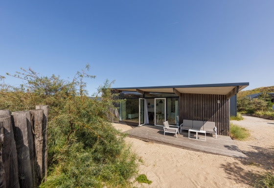 Lodge Sea House Royal moderne à Bloemendaal aan Zee, Pays-Bas, avec terrasse en bois et sable.