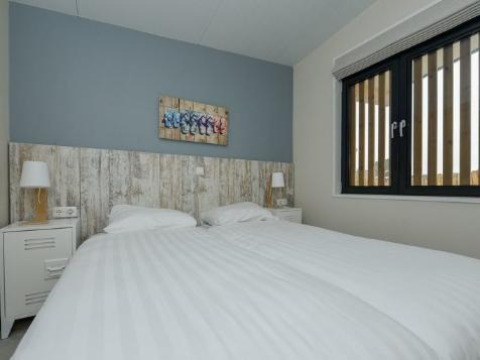 Chambre moderne avec lits jumeaux à la lodge Sea House Royal, Bloemendaal aan Zee, Pays-Bas, avec grande fenêtre.