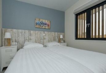 Modern bedroom with twin beds at Sea House Royal lodge in Bloemendaal aan Zee, Netherlands, with large window.