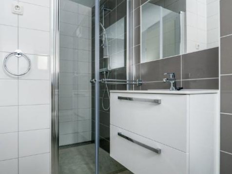 Salle de bain moderne avec douche vitrée, miroir et meuble blanc à Sea House Royal à Bloemendaal aan Zee, Pays-Bas.