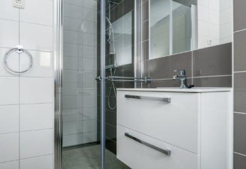 Salle de bain moderne avec douche vitrée, miroir et meuble blanc à Sea House Royal à Bloemendaal aan Zee, Pays-Bas.