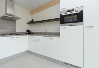 Moderne Küche mit weißen Schränken und Einbauofen im Sea House Royal, Bloemendaal aan Zee, Niederlande.