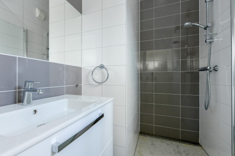 Salle de bain moderne avec douche carrelée grise et lavabo blanc à Sea House Family, Bloemendaal aan Zee, Pays-Bas.