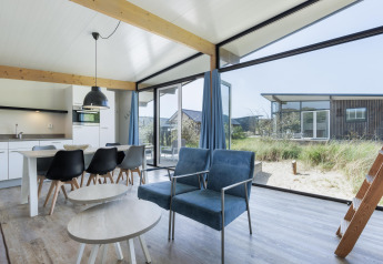 Bright, modern interior of Sea House Family lodge at Bloemendaal aan Zee, Netherlands, with dune views outside.