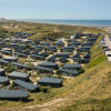 Panoramic photo of Bloemendaal aan Zee holiday park with cottages, dunes, and sea view in North Holland, Netherlands.