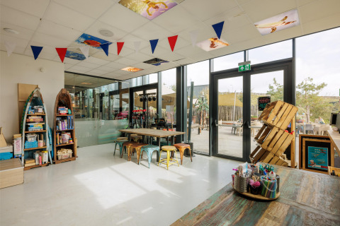 Sala de juegos luminosa con suministros de manualidades y grandes ventanales en Bloemendaal aan Zee, Holanda.