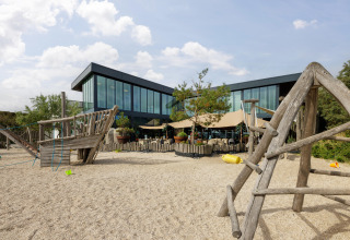 Aire de jeux avec structures en bois devant un bâtiment moderne au parc de vacances Bloemendaal aan Zee, Hollande.