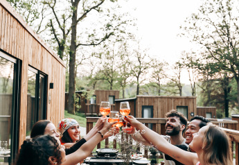 Vrienden eten en proosten samen buiten bij een Ecolodge tiny house in België.