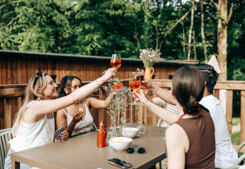 Vrienden proosten met drank buiten bij de Ecolodge tiny house in Hameau de l'Ourthe, België.