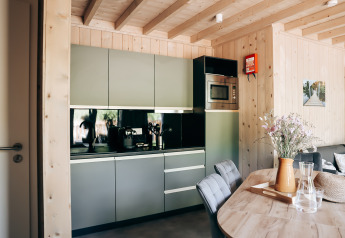 Moderne keuken in de houten Ecolodge tiny house bij Hameau de l'Ourthe, België, met eettafel en bloemen.
