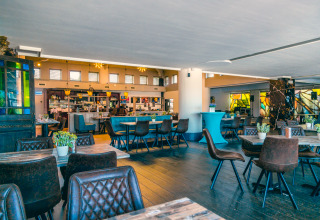 Ristorante moderno e luminoso in una struttura glamping, con tavoli in legno e sedie in pelle.