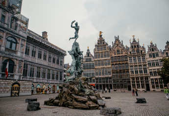 Et historisk torv med en stor statue i midten, omgivet af gamle bygninger og folk i Antwerpen, Belgien.