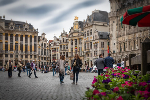 Wandelaars op het Brusselse historische plein, omringd door prachtige gebouwen en kleurrijke bloemen.