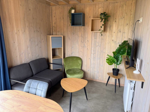 Zona giorno moderna nella Mobi Lodge ad Arden Parks Tulderheyde, Belgio, con rivestimenti in legno e arredi eleganti.