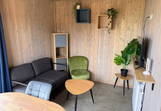 Zona giorno moderna nella Mobi Lodge ad Arden Parks Tulderheyde, Belgio, con rivestimenti in legno e arredi eleganti.