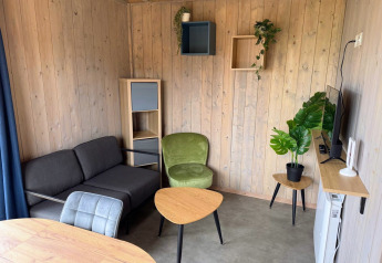 Zona giorno moderna nella Mobi Lodge ad Arden Parks Tulderheyde, Belgio, con rivestimenti in legno e arredi eleganti.
