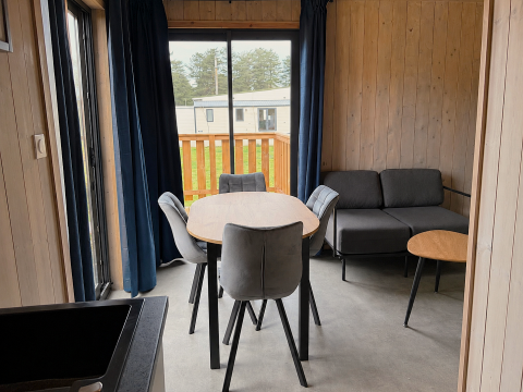 Soggiorno moderno in Mobi Lodge presso Arden Parks Tulderheyde, Belgio, con tavolo da pranzo e divano.