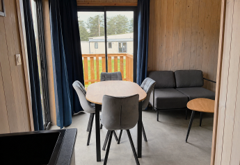 Soggiorno moderno in Mobi Lodge presso Arden Parks Tulderheyde, Belgio, con tavolo da pranzo e divano.