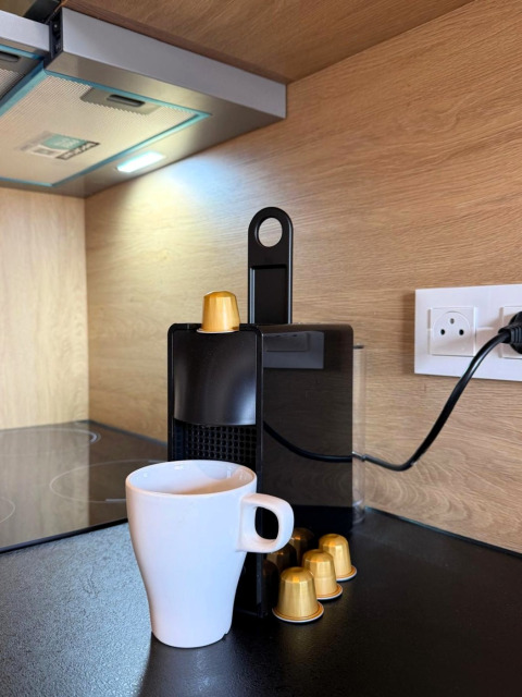 Macchina da caffè con capsule dorate e tazza bianca presso Mobi Lodge, Arden Parks Tulderheyde, Belgio.