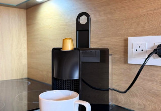 Macchina da caffè con capsule dorate e tazza bianca presso Mobi Lodge, Arden Parks Tulderheyde, Belgio.