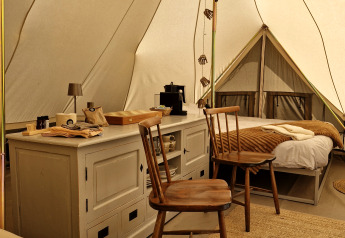Gezellig interieur van een Bell tent bij Thuysgrond in Nederland met houten stoelen en zachte bedden.