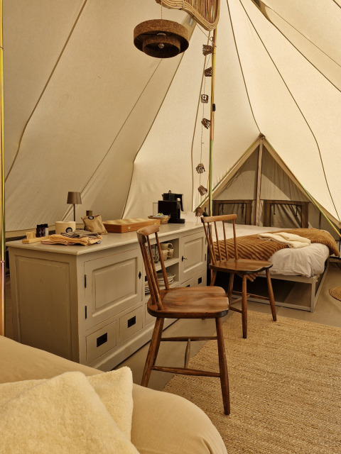 Interieur van een Bell tent bij Thuysgrond in Nederland, met houten stoelen, bedden en warme sfeer.